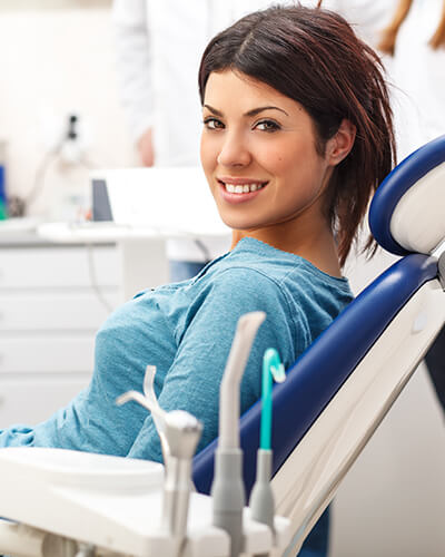 A young woman sitting in the dentist's chair while smiling and waiting for her consultation